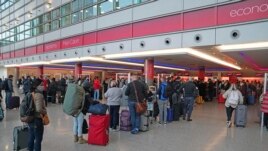 Passengers queue at London Heathrow Airport's T3 as the US reopens its borders to UK visitors in a significant boost to the travel sector, in London, Monday, Nov. 8, 2021. (Steve Parsons/PA via AP)