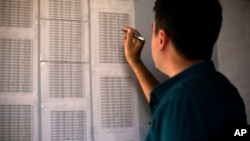 FILE - Bahzad Farhan Murad points to a list of missing and killed Yazidis to The Associated Press in the small office where he collects evidence on Islamic State crimes against Yazidis, in Dohuk, Iraq, May 22, 2016.