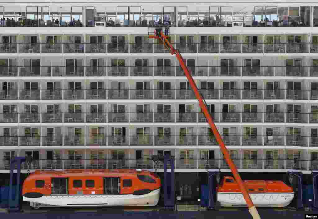 Crew members use a crane to clean windows on the cruise liner Mein Schiff 3 in Valletta&#39;s Grand Harbour, Malta, June 28, 2015.