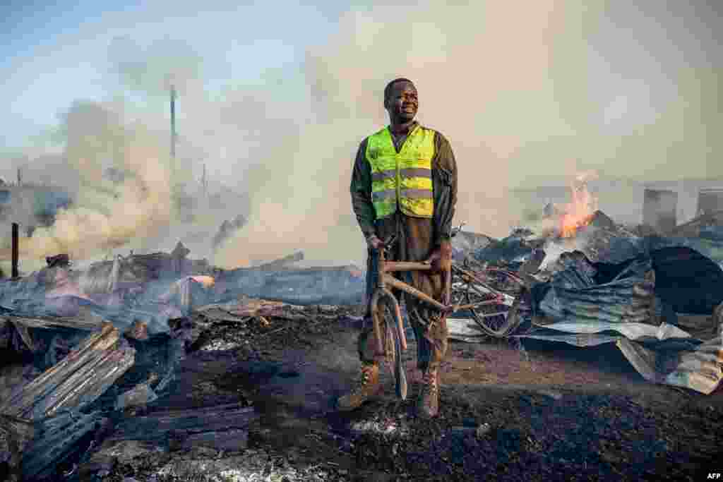 A resident who helps firefighters holds a burnt bicycle after a fire at Toi Market selling second hand clothes at Kibera slum in Nairobi, Kenya.