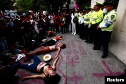 FILE - Women lie on the ground during a performance in front of traffic police officers on the sidelines of a demonstration to demand justice for women who are the victims of violence, in Mexico City, March 8, 2013.