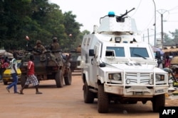 FILE - Police officers from the United Nations Multidimensional Integrated Stabilization Mission in the Central African Republic (MINUSCA) in an armored vehicle patrol a market in Bangui’s Combattant district, Sept. 14, 2015.