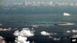 FILE - This aerial photo taken through a glass window of a military plane shows China's alleged on-going reclamation of Mischief Reef in the Spratly Islands in the South China Sea, May 11, 2015.