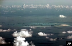 FILE - This aerial photo taken through a glass window of a military plane shows China's alleged reclamation of Mischief Reef in the Spratly Islands in the South China Sea, May 11, 2015.