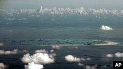 FILE - This aerial photo taken through a glass window of a military plane shows China's alleged on-going reclamation of Mischief Reef in the Spratly Islands in the South China Sea, May 11, 2015.