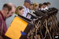 FILE - Voters use electronic voting machines at the Schiller Recreation Center polling station on election day, Nov. 3, 2015, in Columbus, Ohio.