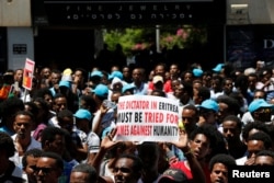 FILE - Eritrean refugees hold placards during a demonstration in support of a recent U.N. report that accused Eritrean leaders of committing crimes against humanity, outside the E.U. offices in Ramat Gan, Israel, June 21, 2016.