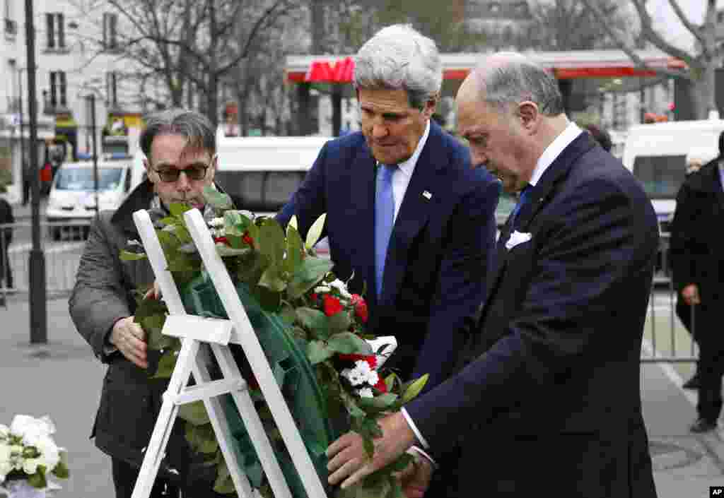 Menteri Luar Negeri AS John Kerry menaruh karangan bunga dengan Menteri Luar Negeri Perancis Laurent Fabius di salah satu tempat serangan teroris, pasar swalayan Yahudi Hyper Cacher di Paris (16/1). ​(AP/Rick Wilking)