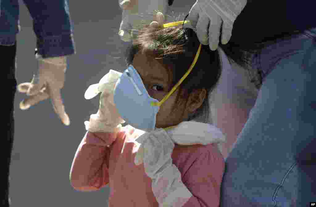 A girl is helped with her mask before traveling with her family to her home province of Piura, at the bus station in Lima, Peru.