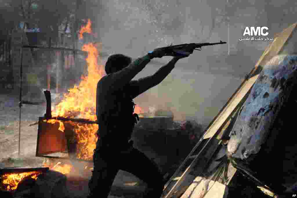 This citizen journalism image provided by Aleppo Media Center shows a Free Syrian Army fighter firing an AK-47 during a battle against the Syrian army loyal to Bashar Assad in Aleppo, Nov. 8, 2013. 