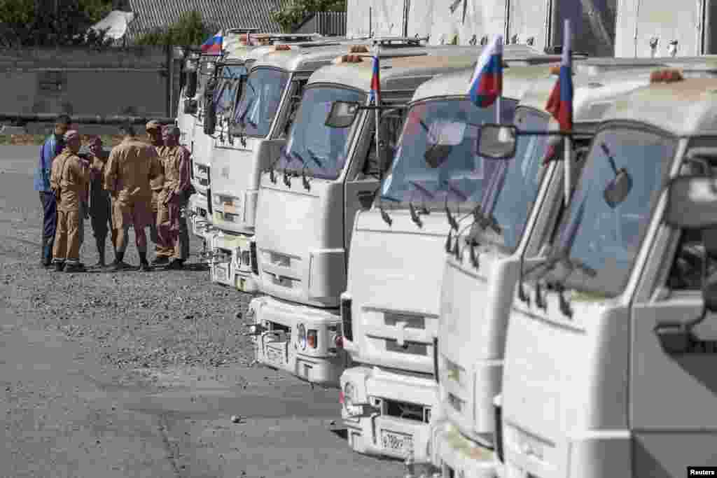 People stand near a Russian convoy of trucks carrying humanitarian aid in Donetsk, eastern Ukraine, Sept.0, 2014.