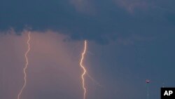 Lightning strikes over a field near wind turbines in Treplin, Germany, June 12, 2019. (Patrick Pleul/dpa via AP)