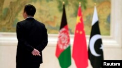 FILE - A security worker stands near, from left, Afghan, Chinese and Pakistani flags during the 1st China-Afghanistan-Pakistan Foreign Ministers Dialogue in Beijing, Dec. 26, 2017. China, Afghanistan and Pakistan over the past two years have launched a trilateral engagement at the foreign ministers level, and the three sides are scheduled to meet in Kabul for another round of talks later this year.