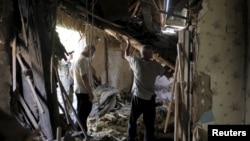 우크라이나 동부 도네츠크의 주거지역이 18일 밤 폭격을 받은 가운데 주민들이 파괴된 건물 안에서 잔해물을 정리하고 있다.