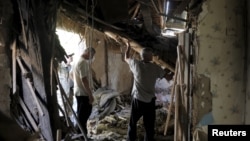 Residents remove debris inside a damaged building, which according to locals was caused by recent shelling, in Avdiivka in the Donetsk region, Ukraine, July 18, 2015.