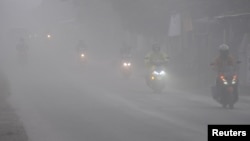 Para pengendara motor mengendarai motor di tengah hujan debu abu vulkanik dari erupsi Gunung Merapi, Boyolali, Jawa Tengah, 3 Maret 2020. (Foto: Antara via Reuters)