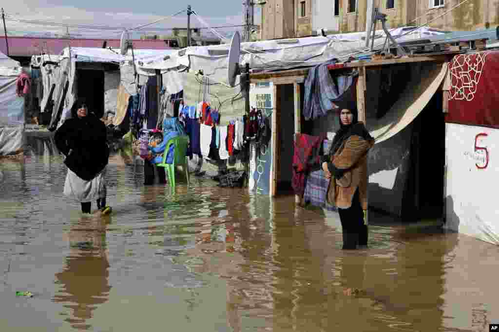 Syrian refugees stand in a pool of mud and rain water at a refugee camp, in the town of Bar Elias, in the Bekaa Valley, Lebanon.