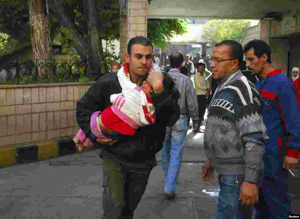 A man carries an injured child after a bomb explosion in front of the al-Hejaz train station in central Damascus, Syria. A bomb exploded in central Damascus, killing eight people and wounding 50, with women and children among the casualties, SANA said. (Photo provided by Syria's national news agency SANA)