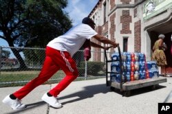 Teacher Cedric Cook pushes cases of water into Noble School in Detroit, Sept. 4, 2018. Some 50,000 Detroit public school students began the school year last month by drinking water from coolers, not fountains, after the discovery of elevated levels of lead or copper — the latest setback in a state already dealing with the consequences of contaminated tap water in Flint and other communities.