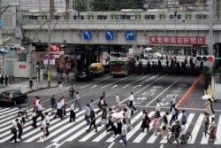 Para pejalan kaki berjalan melintasi penyeberangan jalan yang ramai di dekat Stasiun Ueno, Tokyo, Jumat, 30 Juli 2021. (AP)