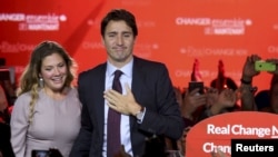 ທ່ານ Justin Trudeau ຜູ້​ທີ່​ໄດ້​ນຳພາ​ພັກ​ເສລີນິຍົມ ​ ຢືນຢູ່ກັບພັນລະຍາ ທ່ານນາງ Sophie Gregoire, ໃນຂະນະທີ່ທ່ານ ກ່າວຄຳປາໄສ ຮັບເອົາໄຊຊະນະ. 