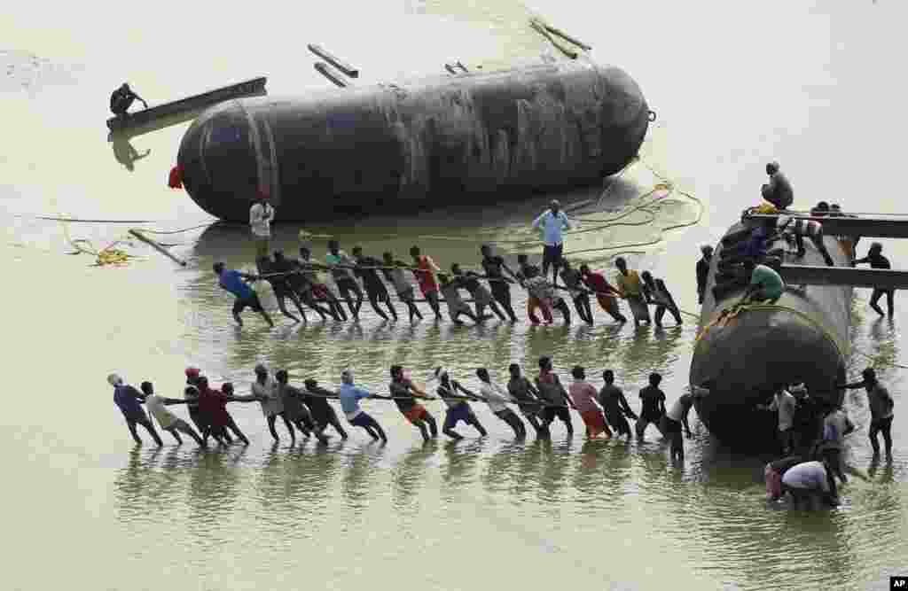 Laborers use a rope to pull a pontoon buoy in the River Ganges as they build a floating bridge for the upcoming Kumbh Mela festival, in Allahabad, India.