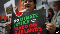 Una activista muestra un cartel que dice "No hay justicia climática con sangre en nuestras tierras" durante la conferencia COP29 de la ONU enBakú, Azerbaiyán, el 14 de noviembre de 2024.