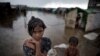 In this June 26, 2014 photo, a girl, self-identified as Rohingya, stands close to her family's tent house at Dar Paing camp for refugees, suburbs of Sittwe, Western Rakhine state, Myanmar. Suu Kyi's many supporters overseas have been dismayed by her…