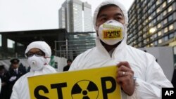 A Greenpeace activist holds a placard during a demonstration outside Japan's Prime Minister Yoshihiko Noda's official residence in Tokyo, criticizing the government's declaration of cold shutdown at the Fukushima nuclear power plant, December 16, 2011.