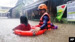 ໃນຮູບທີ່ໄດ້ແຈກຢາຍ ໂດຍໜ່ວຍຍາມຝັ່ງຂອງຟີລິບປິນ, ເຈົ້າໜ້າທີ່ກູ້ໄພທ່ານນຶ່ງໄດ້ຊ່ວຍເຫຼືອເດັກນ້ອຍຍິງຄົນນຶ່ງ ໃນຂະນະທີ່ພວກເຂົາເຈົ້າພາກັນລຸຍນໍ້າຖ້ວມ​ທີ່ເປັນຜົນມາຈາກພາຍຸໄຕ້ຝຸ່ນ ໄຣ, ໃນເມືອງຄາກາຢານ ເດີ ໂອໂຣ, ປະເທດ ຟີລິບປິນ, ວັນທີ 16 ທັນວາ 2021.