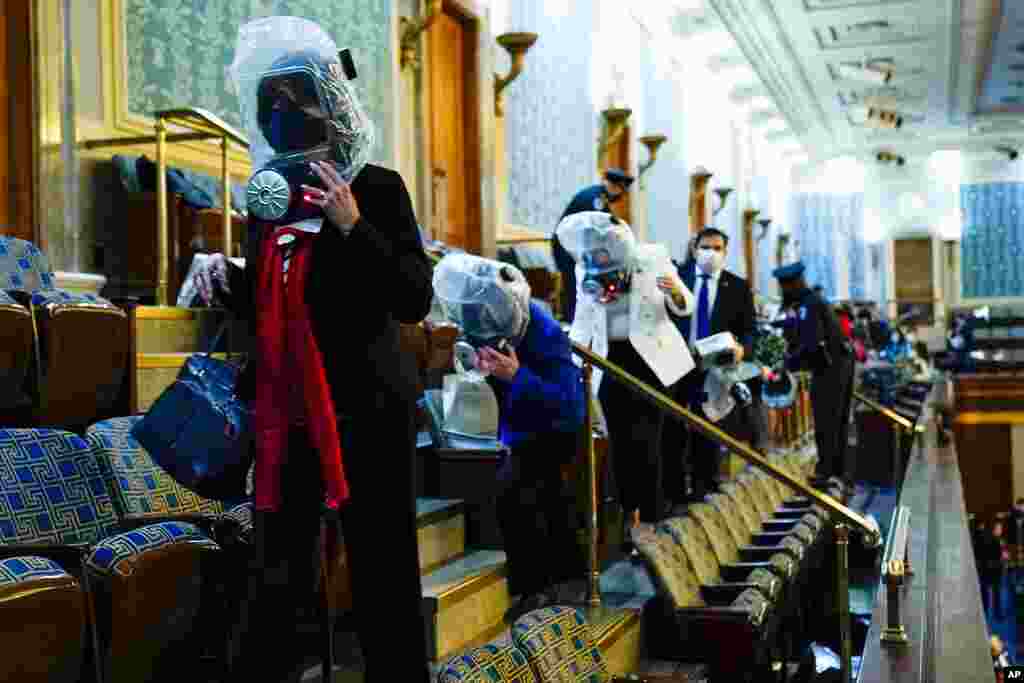 People shelter in the House gallery as protesters try to break into the House Chamber at the U.S. Capitol, Jan. 6, 2021, in Washington.