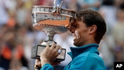 Petenis Spanyol Rafael Nadal mengangkat trofi juara turnamen Perancis Terbuka di stadion Roland Garros, Paris, hari Minggu (10/6). 
