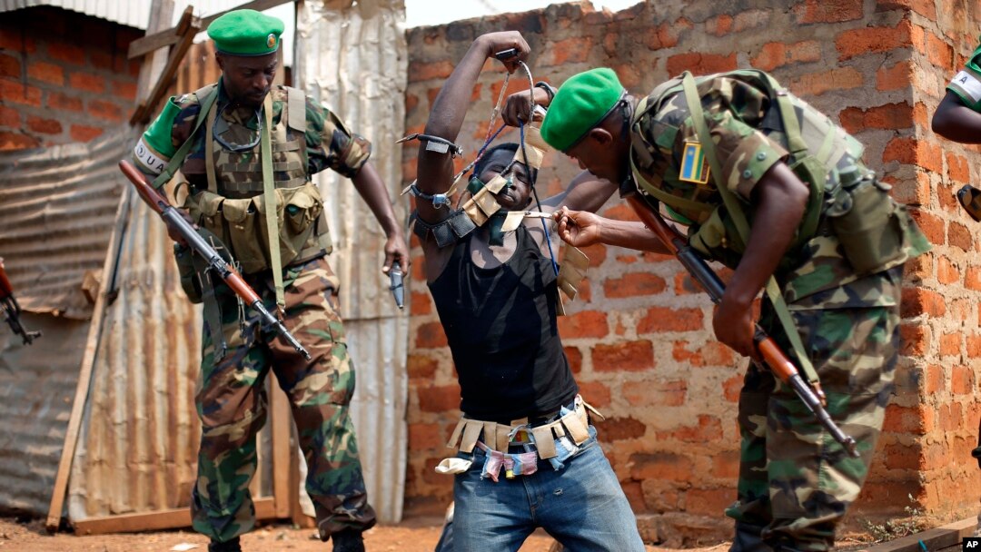 Rwandan African Union peacekeepers remove the lucky charms from a suspected Anti-Balaka Christian man who was found with a rifle and a grenade following looting in the Muslim market of the PK13 district of Bangui, Central African Republic, Jan. 22, 2014. 