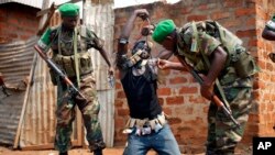 Rwandan African Union peacekeepers remove the lucky charms from a suspected Anti-Balaka Christian man who was found with a rifle and a grenade following looting in the Muslim market of the PK13 district of Bangui, Central African Republic, Jan. 22, 2014. 