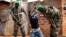 Rwandan African Union peacekeepers remove the lucky charms from a suspected Anti-Balaka Christian man who was found with a rifle and a grenade following looting in the Muslim market of the PK13 district of Bangui, Central African Republic, Jan. 22, 2014. 