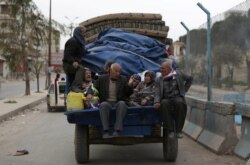 FILE - People ride in a truck with their belongings in the center of Afrin, Syria, March 24, 2018.