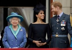 FILE - Britain's Queen Elizabeth II, and Meghan the Duchess of Sussex and Prince Harry watch a flypast of Royal Air Force aircraft pass over Buckingham Palace in London, July 10, 2018.