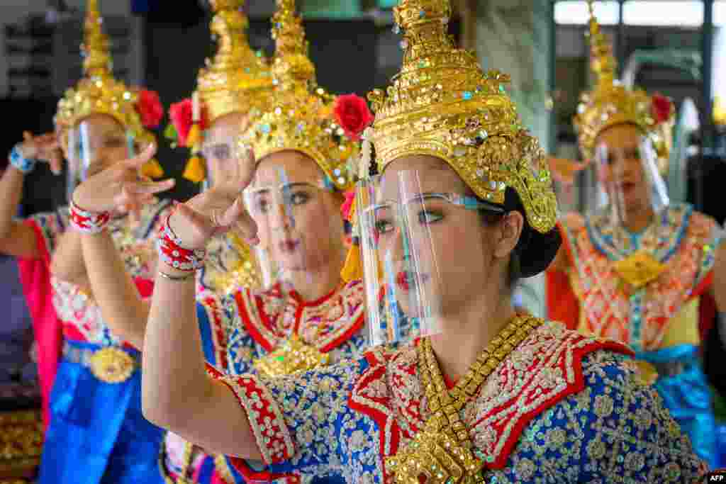 អ្នករាំរបាំថៃពាក់បន្ទះផ្លាស្ទិកការពារមុខអំឡុងពេលធ្វើការសម្តែងមួយនៅអាស្រម Erawan បន្ទាប់ពីរដ្ឋាភិបាលថៃបានបន្ធូរបន្ថយវិធានការរឹតត្បិតដើម្បីប្រយុទ្ធប្រឆាំងនឹងជំងឺកូវីដ១៩ នៅក្រុងបាងកក។&nbsp;