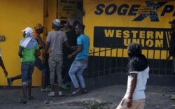 Protesters loot a money transfer office during a protest demanding the resignation of President Jovenel Moise in Port-au-Prince, Haiti, June 13, 2019.