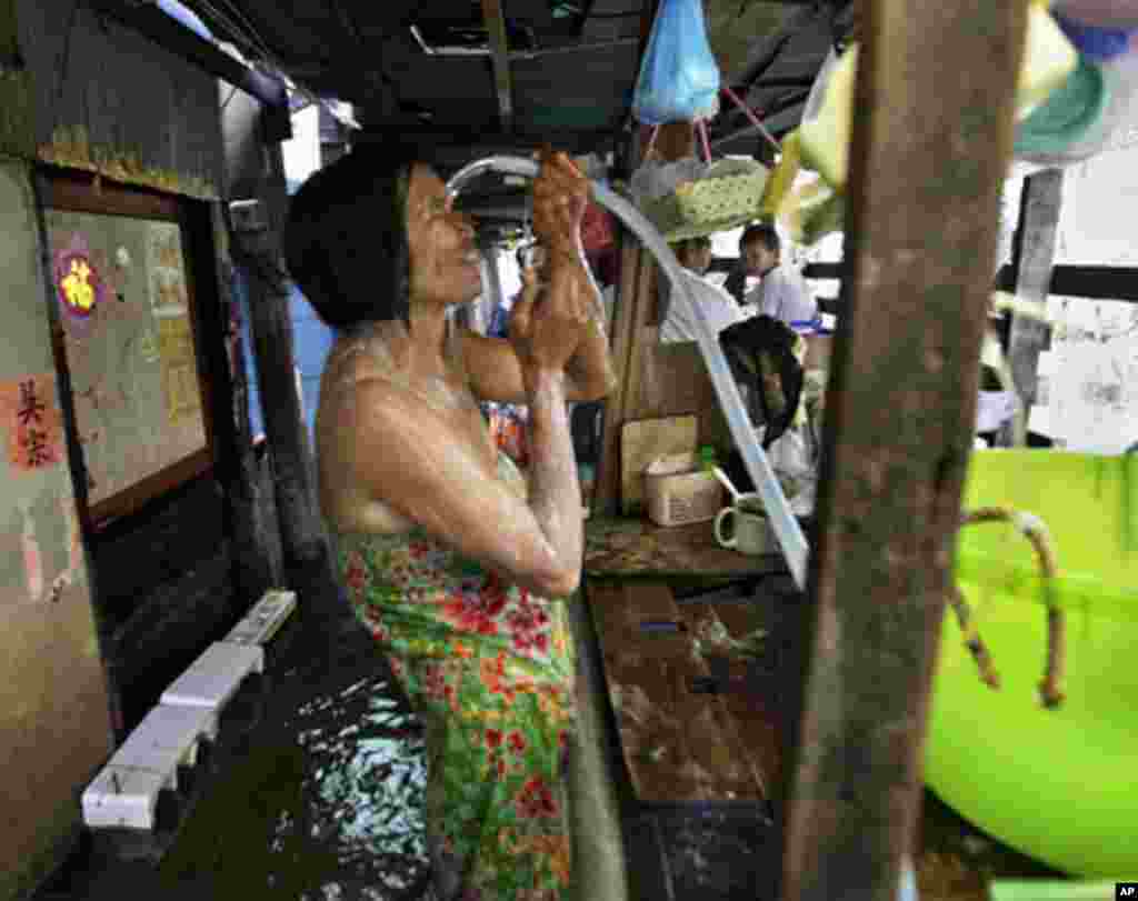 A Thai woman takes a shower in a narrow alley in a flooded neighborhood in Bangkok, Thailand, November 8, 2011.