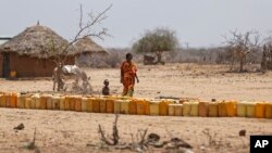 Une femme et son enfant passe une container d'eau, au nord du Kenya, le 3 mars 2017.