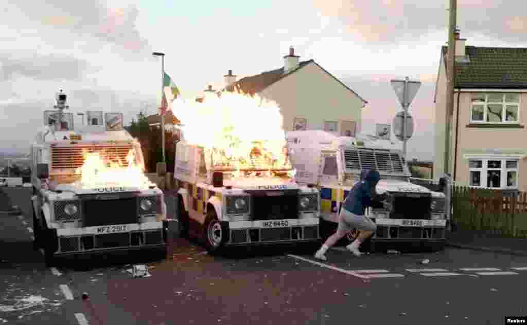 A person runs after throwing a petrol bomb at PSNI vehicles, following a security alert that was issued due to a suspicious package found in Creggan Heights, Derry, Northern Ireland, in this still image obtained from a social media video.