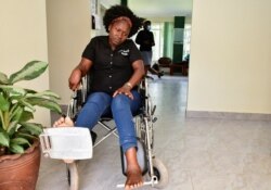 FILE - Irene Abalo, a journalist working with The Daily Monitor newspaper, sits on a wheelchair after she was injured in an attack by security officials, outside the UN Human Rights offices while on reporting duty, in Kampala, Uganda Feb. 17, 2021.