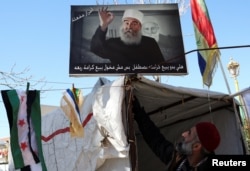 لەم دیمەنەدا وێنەی سەرکردەی دروزەکان شێخ حیکمەت هەجەری هەڵواسراوە.
