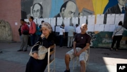 Dos electores aguardan antes de depositar su voto mientras otros examinan listas para ver dónde deben votar durante los comicios locales en Caracas, Venezuela, el domingo 9 de diciembre de 2018.