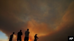Residents of villages watch a fire in the Larnaca mountain region on July 3, 2021. 