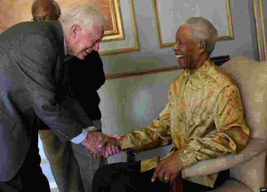 L'ancien président américain Jimmy Carter salue Nelson Mandela (assis) le 29 mai 2010 lors d'un déjeuner privé à Johannesburg. (Photo Jeff Moore /AFP)