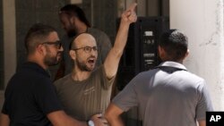 FILE - An Israeli settler heckles Israelis protesting near the home of far-right National Security Minister Itamar Ben Gvir against plans by Benjamin Netanyahu's government efforts to overhaul the judiciary, in the West Bank settlement of Kiryat Arba, August 25, 2023.