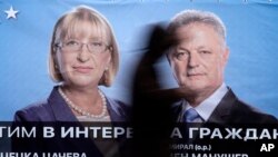 A man passes in front of a poster of Bulgaria's GERB party presidential candidate Tsetska Tsacheva and vice-president Plamen Manushev in Sofia, Nov. 4, 2016. Bulgarians will to choose their new president Sunday.