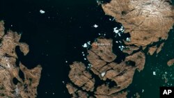 The satellite image, which was captured by Sentinel-2A on July 9, 2018, provided by European Space Agency esa on July 18, 2018 shows a huge iceberg perilously close to the village of Innaarsuit on the west coast of Greenland.